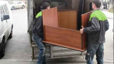 грузчики затаскивают стол в грузовую газель